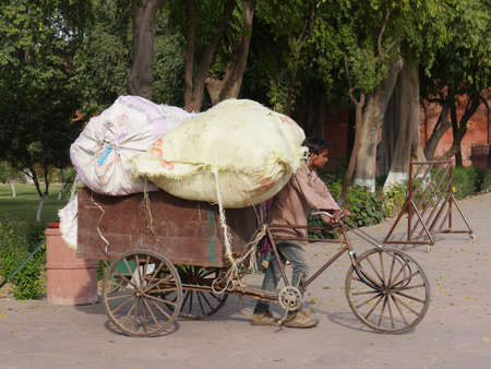 Agra, Uttar Pradesh, India- March 2018: A man pushes an overloaded bicycle-drawn cart on the road in...