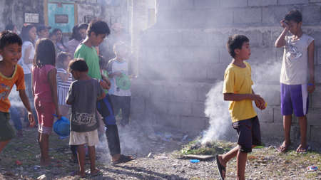 Tagum City, Philippines- March 2016: Following a superstitious belief, children walk over a small bonfire after burying a dead relative.のeditorial素材