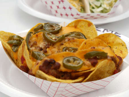 Nachos on a paper plate loaded with jalapeno, meat and melted cheeseの写真素材