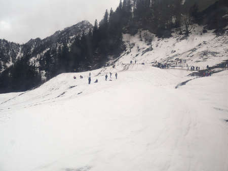 Unrecognizable people enjoy the snowy slopes of Solang Valley, Himalayas.