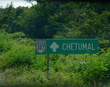 Directional sign by the road in Costa Maya with arrows pointing to the direction of Chetumal, about 142 kilometers away.の写真素材