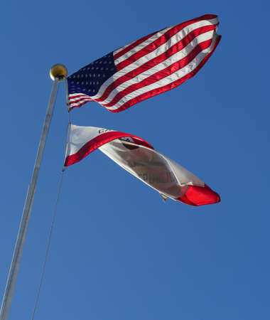 Flag of the United States of America flying up with the California Republic flag furled waving downward from one flagpoleの写真素材