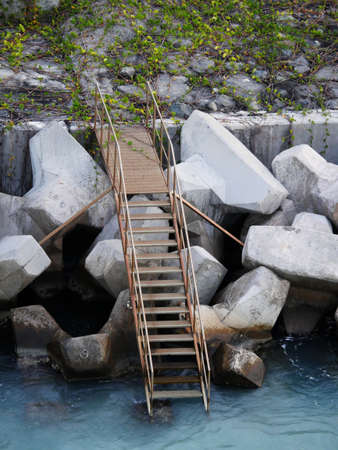 Metal stairs extending down to the water from a cement wall