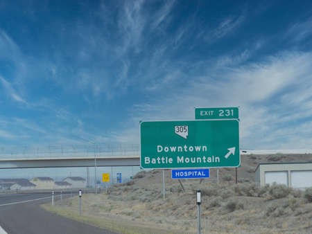 Wide shot of a roadside sign at Highway 80 in Nevada with directions to Downtown Battle Mountain.