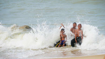 NARATHIWAT, THAILANDâMARCH 2016:  Boys happily splashing with the huge waves at a beach in Narathiwat, southernmost part of Thailand near the Malaysian border.のeditorial素材