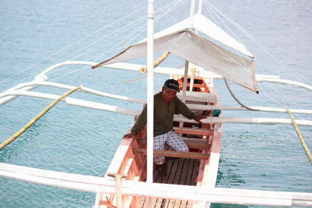 SURIGAO DEL SUR, PHILIPPINESâAUGUST 2014: A boat operator sits inside the boat waiting to transport passengers to nearby islands.のeditorial素材