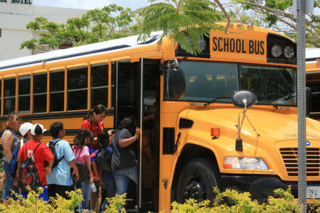 SAIPAN, CNMIâ€”Students and their chaperones board a school bus at a field trip in Saipan,...