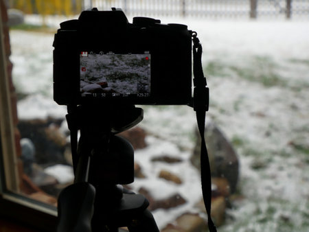 Close up of a camera filming a winter scene from the windowの写真素材