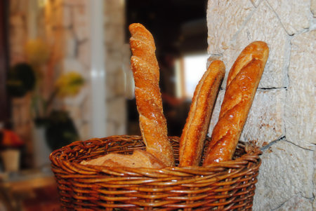 Baguettes in a wicker basket on the background of a stone wallの写真素材