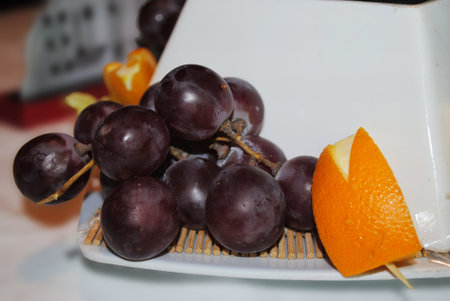 Grapes and orange on a white plate, closeup of photoの写真素材