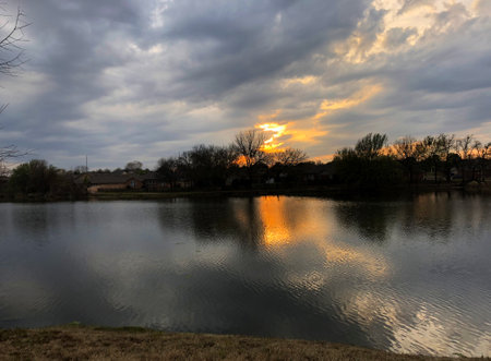 Sunset over a lake with reflection in the water and cloudy skyの写真素材