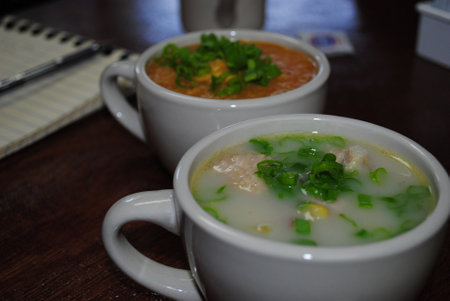 Two cups of different soups with slices of green onions on top.の写真素材