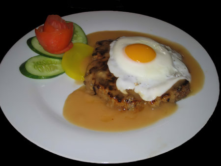 Steak with egg and vegetables on a white plate in a restaurantの写真素材