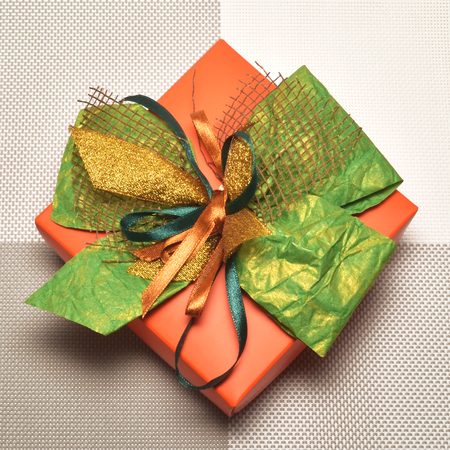 Beautiful Christmas orange gift box with green bowの写真素材
