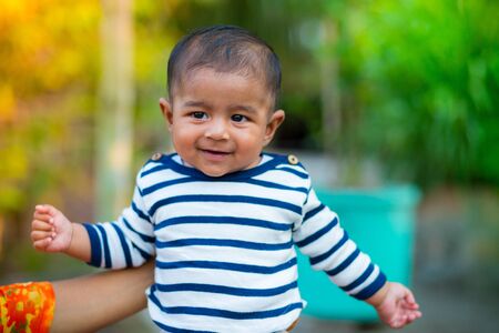 A baby boy looking and smiling. Dressed are white and navy blue striped dress. Baby candid shoot....