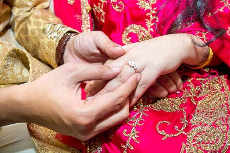 Bride places the wedding ring on the Groomâs finger at Bangladesh. Close up image.の写真素材