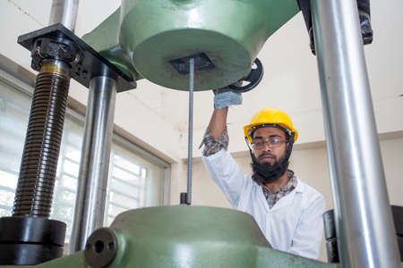 Bangladesh â€“ May 20, 2015: A factory lab operator using Steel rod strength testing machine at...