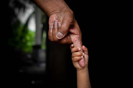 A baby's hands holding tightly A senior man's old age finger. Family, Generation, Support and people...