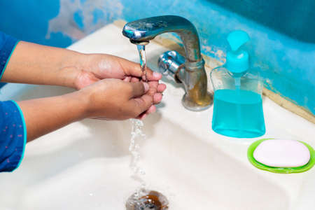 Women use liquid soap for rubbing and washing her hands under the water tap. Hygiene concept. Wash...