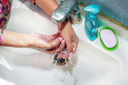 Women use liquid soap for rubbing and washing her hands under the water tap. Hygiene concept. Wash hands to stop spreading coronavirus.の写真素材