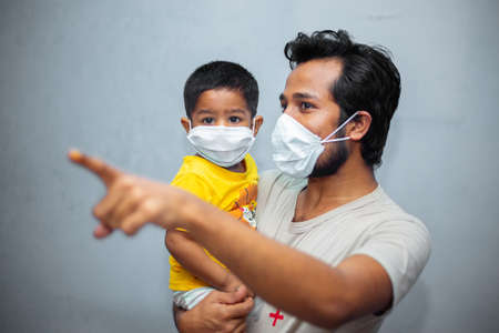 A young man and little Asian toddler boy wearing a face mask for Coronavirus safety. Coronavirus pandemic.の写真素材