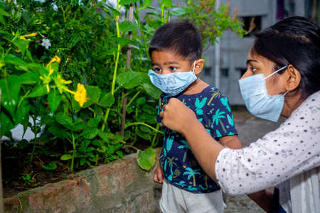 Little boy and mom wearing medical mask. A little boy and mom are traveling in the garden. Protect from the coronavirus infection on home quarantine.の写真素材