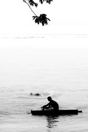 Two boys are bathing on river water and having fun. Image of against sunlight. Silhouette image.の写真素材