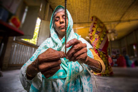 An old age woman is making on some fiber rope using on the banana tree fiber at Madhupur, Tangail,...