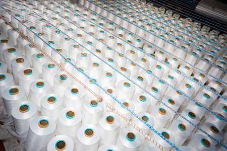 Top view of A lot of white yarn spools in a textile factory. White yarn spools in a clothing...