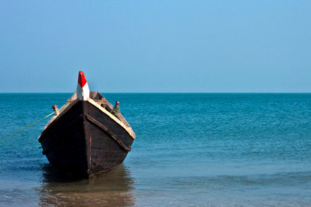 A lone wooden boat floating in the waters of the blue sea.