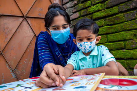 Bangladesh â August 02, 2021: In the lockdown and home quarantine of the Covid-19 epidemic, an Asian mother is teaching her child at home wearing a mask at Joypara, Dohar, Dhaka.のeditorial素材