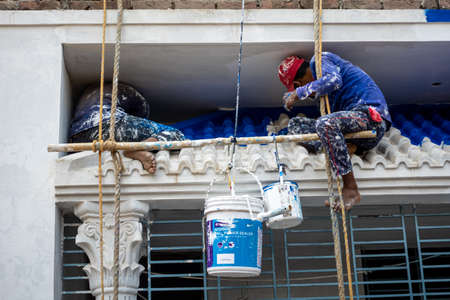 Bangladesh â February 18, 2021: Two workers painting on the cement wall of a building in dangerous and risky ways at Joypara, Dohar, Dhaka.のeditorial素材