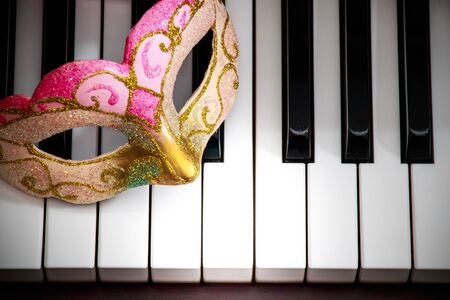colorful and beautiful face mask on the black and white piano keyboard keys backgroundの写真素材
