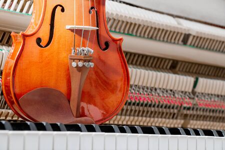brown classical violin on the piano keyboard with inside the wall piano backgroundの写真素材