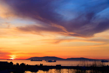 Amazing colors of sunset in the port with reflections of calm sea - focus is on the horizons