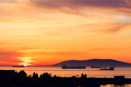 Amazing colors of sunset in the port with reflections of calm sea - focus is on the horizonsの写真素材