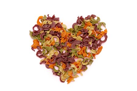 Dried pasta in heart shape top view. Colorful vegetable pastas on isolated backgroundsの写真素材