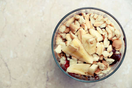 Delicious dessert with banana and biscuits chocolate pudding in glass cup on table background