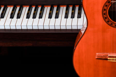 close up of classic guitar over piano keys for music background with copy space