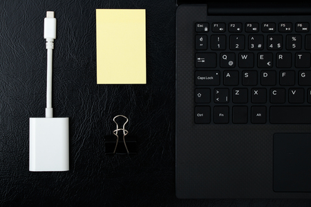 Overhead of office table with laptop, computer keyboard and sticky notepad, ports adapterの写真素材