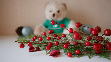 Christmas decorations With a teddy bear, pine branches, cherry branches and red flowers with bead.