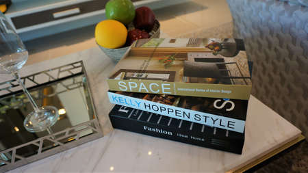 The living room has a glass tray for drinking glasses and beverage with books and fruits on marble...