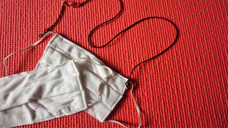 Two white masks with neck strap put on a yoga mat because exercise must also have the prevention of COVID-19.の写真素材