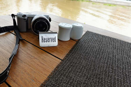 The table reservation sign is set on a placemat made of black weave material, complete with a bottle...