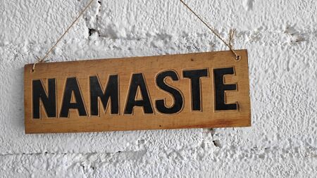 The words "NAMASTE" on the wooden boards are posted on the white walls (NAMASTE  has meaning I bow to you)の写真素材