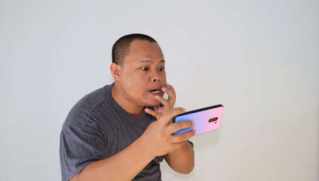 Man angry with his smartphone, with a stressed expression. Emotional due to info from his smartphone