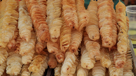 Potato chips on a stick. Natural chips are fried and sold at the fair. Fat street food.