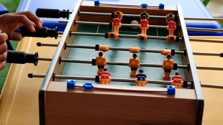 close up of a person hands playing foosball, turning the handles on a table soccer game. Plastic...