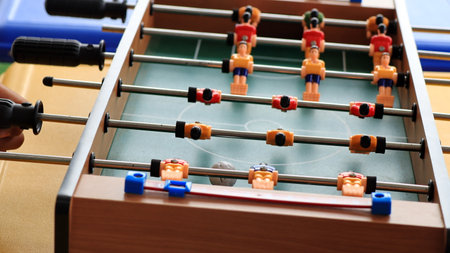 close up of a person hands playing foosball, turning the handles on a table soccer game. Plastic...