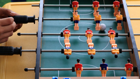 close up of a person hands playing foosball, turning the handles on a table soccer game. Plastic...